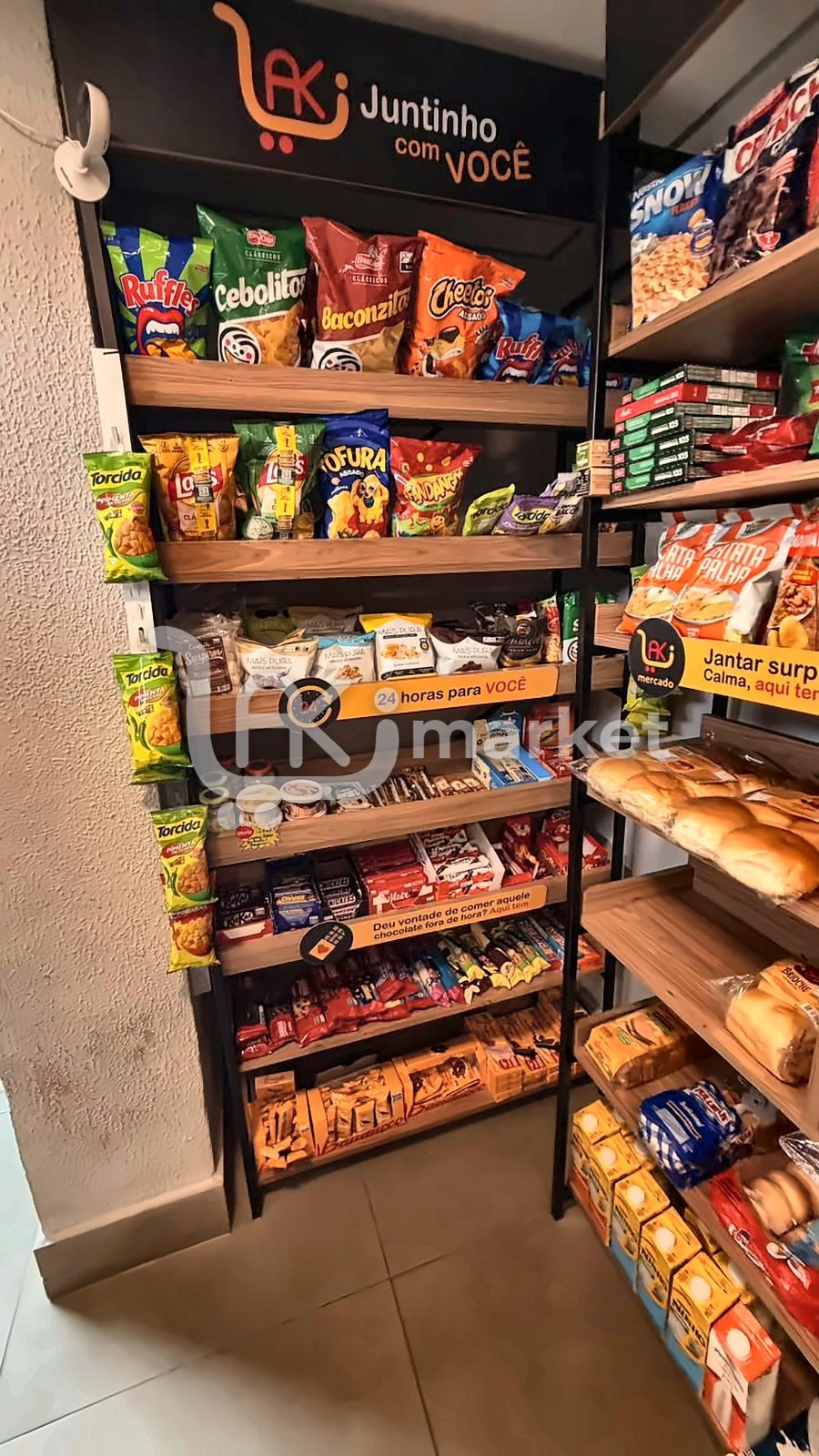Prateleira Juntinho com Você, com salgadinhos, doces e a placa 24 horas para você.