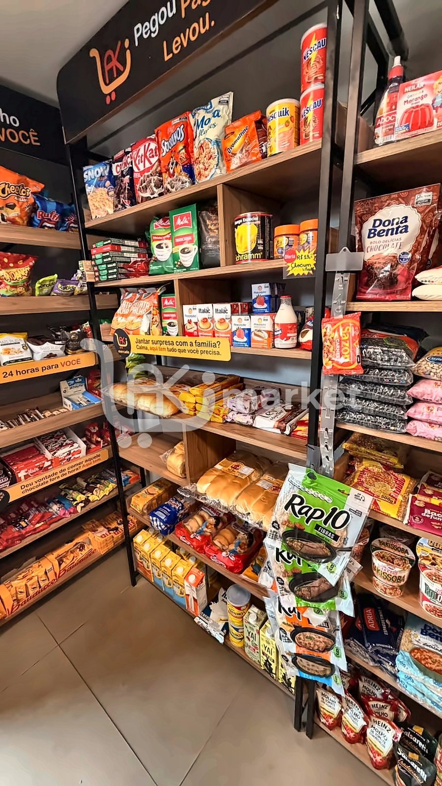 Gôndola de mercearia de uma loja Waki com café, massas, pães e a placa: Jantar surpresa com a família? Calma, aqui tem tudo que você precisa.
